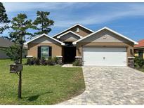 Charming single-story home with a well-manicured lawn, brick driveway, and neutral-toned exterior at 6836 Sw 179Th Court Rd, Dunnellon, FL 34432