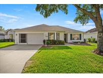 Charming single-story home with a well-maintained lawn and attached garage, under a blue sky at 1308 La Estrellita Way, The Villages, FL 32162