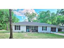 Charming single-story home with a well-manicured lawn, tidy landscaping, and a cheerful light-blue front door at 19370 Saint Benedict Dr, Dunnellon, FL 34432