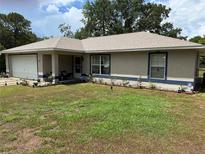 Charming single-story home featuring a well-maintained lawn and an attached garage at 27 Cedar Tree Ter, Ocala, FL 34472