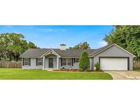 Charming single-story home featuring a gray exterior, attached garage, manicured lawn, and a traditional architectural style at 380 Ne 53Rd St, Ocala, FL 34479