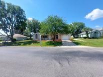 Charming single-story home with a well-manicured front yard and a paved driveway under a clear blue sky at 5110 Nw 19Th Pl, Ocala, FL 34482