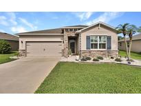 Charming home featuring a stone facade, well-manicured lawn, and a two-car garage at 6405 Sw 88Th Loop, Ocala, FL 34476