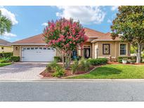 Charming home featuring a brick driveway, manicured lawn, and vibrant landscaping with a beautiful, flowering tree at 8737 Sw 83Rd Cir, Ocala, FL 34481