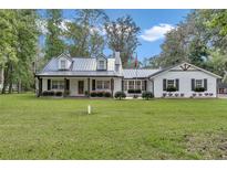 Charming single-story home featuring manicured lawn and metal roof at 12677 Se 53Rd Terrace Rd, Belleview, FL 34420