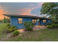 Charming single story home with blue siding and a cozy front porch at sunset at 17128 Se 140Th Ave, Weirsdale, FL 32195