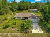 Aerial view of a charming single-story home with a well-manicured lawn, mature trees, and fenced yard at 3445 Se 139Th Ln, Summerfield, FL 34491