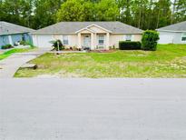 Inviting single-story home with a well-maintained lawn, neat landscaping, and a cozy front porch at 9 Bahia Trace Loop, Ocala, FL 34472