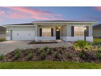 Charming single-story home featuring a well-manicured lawn, brick driveway, two car garage, and welcoming front porch at 9865 Sw 105Th Ct, Ocala, FL 34481