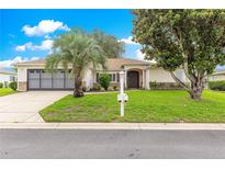 Charming home featuring a well-manicured lawn and a classic exterior design with mature trees at 13715 Se 88Th Ct, Summerfield, FL 34491