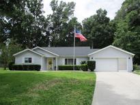 Charming single-story home with manicured lawn, attached garage, and a US flag on display at 14192 Sw 112Th Cir, Dunnellon, FL 34432