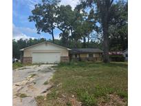 Modest single-story home with an attached garage and overgrown landscaping at 1751 Se 39Th St, Ocala, FL 34480