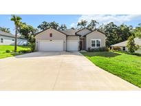 Charming home showcasing a manicured lawn, gray siding, double garage, and lush surrounding trees at 19551 Sw 77Th Loop, Dunnellon, FL 34432