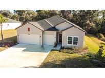 Charming home featuring a three-car garage, neutral siding and manicured lawn at 19551 Sw 77Th Loop, Dunnellon, FL 34432
