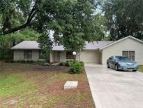 Charming single-story home with a well-maintained lawn, mature trees, and a private driveway leading to an attached garage at 519 Spring Lake Rd, Ocala, FL 34472