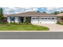 Beautiful single-story home with a well-manicured lawn, three-car garage, and brick-paved driveway at 9886 Sw 104Th Ave, Ocala, FL 34481