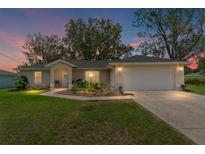 Charming single-story home with a well-manicured lawn and a two-car garage at twilight at 106 Pine Trce, Ocala, FL 34472