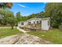 Charming single-story home with a wooden porch and well-maintained lawn at 10671 Ne 152Nd Ln, Fort Mc Coy, FL 32134