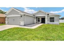 Well maintained gray home featuring a two car garage and inviting front yard at 5133 Sw 41St Pl, Ocala, FL 34474