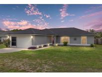 Charming single story home with a well manicured lawn, complemented by a two car garage and lovely sunset skies at 63 Walnut Crse, Ocala, FL 34480