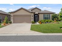 Charming single-story home featuring a well-maintained lawn, manicured shrubs, and a neutral-colored stucco facade at 6776 Sw 95Th Cir, Ocala, FL 34481