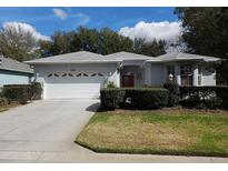 Charming one-story home featuring a well-manicured lawn, a two car garage, and a colorful red front door at 8298 Sw 79Th Cir, Ocala, FL 34476