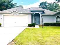 Charming single-story home featuring an attached garage, manicured lawn, and inviting front entrance at 9328 Sw 192Nd Court Rd, Dunnellon, FL 34432
