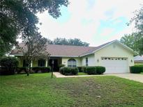 Inviting single-story home with a well-manicured lawn and an attached two-car garage at 95 Hickory Loop, Ocala, FL 34472