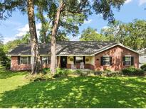 Charming brick and siding home with mature trees and a welcoming front porch with rocking chairs at 986 Se 57Th Ave, Ocala, FL 34480