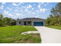 Charming single-story home with a blue garage door, gray exterior and a well-manicured lawn at 142 Guava Pass, Ocklawaha, FL 32179