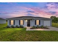 Charming single-story home featuring a well-maintained lawn and inviting front entrance under a colorful dusk sky at 14690 Sw 24Th. Pl, Ocala, FL 34481