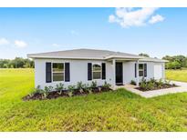Charming single-story home with gray exterior, black shutters, and lush landscaping at 14885 Sw 23Rd Pl, Ocala, FL 34481