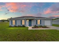 Charming single-story home featuring gray stucco, blue shutters, and a well-manicured lawn at 14893 Sw 23Rd Pl, Ocala, FL 34481