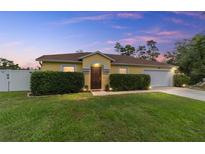 Charming yellow single-story home featuring a well-manicured lawn and lush, green hedges in front at 16605 Sw 31 Cir, Ocala, FL 34473