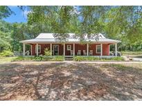 Charming single-story home featuring a cozy front porch with rocking chairs and a well-maintained landscaped yard at 23608 Ne 124 Place Rd, Salt Springs, FL 32134