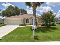 Well-maintained single-story home featuring a lush front lawn with a palm tree and a two car garage at 2478 Nw 50Th Ave, Ocala, FL 34482