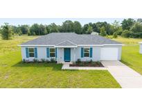 Charming single-story home featuring a well-maintained lawn, blue shutters, and an attached one car garage at 37 Teak Run, Ocala, FL 34472