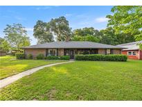 Charming brick home featuring a lush front lawn, mature trees, and a welcoming walkway leading to the front door at 6497 W Anthony Rd, Ocala, FL 34479