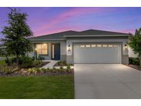 Charming single-story home with a well-manicured lawn and two-car garage, beautifully lit against a colorful evening sky at 8802 Sw 79Th Loop, Ocala, FL 34481