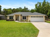 Charming single-story home with a well-manicured lawn, a two car garage and mature landscaping at 9432 Se 159Th Ln, Summerfield, FL 34491