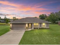Charming single-story home with a well-manicured lawn and neutral color scheme highlighted by a gorgeous sunset at 11 Pecan Course Loop, Ocala, FL 34472