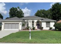Charming single-story home with well-manicured lawn, a purple door, and a two car garage at 11605 Sw 69Th Cir, Ocala, FL 34476