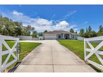 Charming single-story home with a long driveway and a well-manicured lawn, under a bright blue sky at 12392 Sw 85 Pl, Dunnellon, FL 34432
