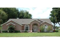 Charming single-story home featuring a well-maintained lawn, arched entryway and front door wreath at 14126 Greater Pines Blvd, Clermont, FL 34711