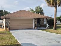 Charming home featuring a stone facade, a spacious driveway, and a well-maintained yard at 21511 Sw Plantation Sw St, Dunnellon, FL 34431