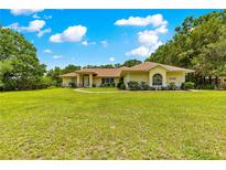 Charming single-story home featuring a well-manicured lawn and mature trees creating a serene setting at 5445 Ne Anthony Rd, Ocala, FL 34475