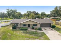 Charming single-story home with a well-maintained lawn, mature trees, and a two-car garage at 6320 Se 42Nd Ct, Ocala, FL 34480