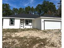 Newly constructed one-story home featuring a white exterior, black trim, and a two-car garage at 7604 Sw 103Rd Loop, Ocala, FL 34476