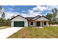 Beautiful single story house with a green garage door and wood-accented porch at 12251 Sw 67Th Ln, Ocala, FL 34481