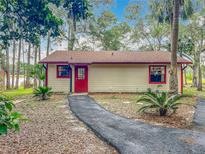 Charming single-story home featuring a vibrant red door and window trim with a natural landscape setting at 16621 Se 57Th Pl, Ocklawaha, FL 32179
